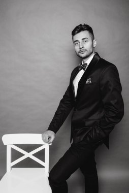 Gri stüdyo arka planında takım elbiseli şık bir iş adamı.