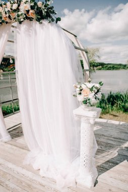 Göl ya da nehir kenarındaki yeşillik ve çiçeklerle süslenmiş güzel yuvarlak düğün kemeri, kopyalama alanı. Düğün için açık ai 'de süslemeler