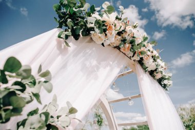 Göl ya da nehir kenarındaki yeşillik ve çiçeklerle süslenmiş güzel yuvarlak düğün kemeri, kopyalama alanı. Düğün için açık ai 'de süslemeler