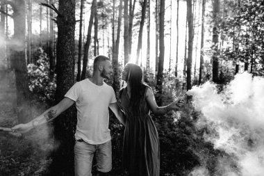 Güzel bir çift, sonbahar ormanının arka planında, dumanın içinde duruyor.. 