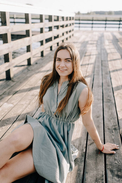 Loving couple sitting on the pier on lake at summer sunset