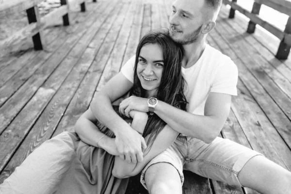 夏の日没に湖の桟橋に座って愛するカップル — ストック写真