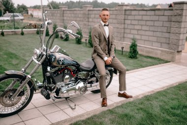 Motosikletli genç bir işadamı spor eldivenleri giyer ve mutlu bir şekilde yan yana bakar.