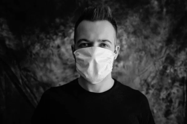 Sick young man with medical face mask portrait close up illustrates pandemic coronavirus disease on dark background. Covid-19 outbreak contamination concept.