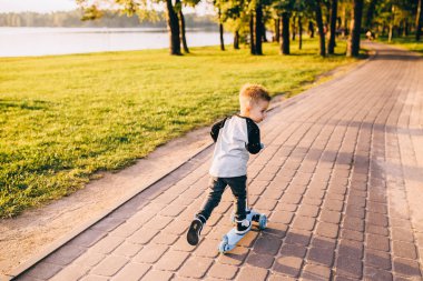 Küçük şirin bir çocuk scooter kullanıyor. Sağlıklı açık hava etkinliği