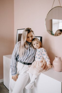 Küçük mutlu anaokulu kızı ve genç anne burunlarına dokunur. Gözlerinin içine bakar, birlikte güzel bir anın tadını çıkarırlar. Gülümseyen anne ve kız çocukları hafta sonları evde oynarken eğlenirler.