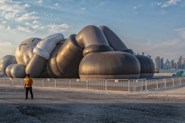 Doha-Katar, 16 Kasım 2019: Doha Cor 'da Kaws Tatil Sanatı kurulumu Gökyüzünde bulutlarla Gün Işığı
