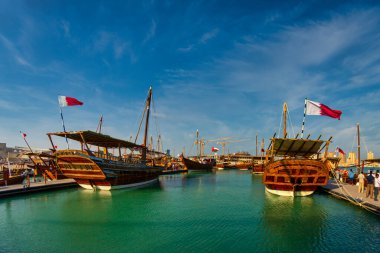 Katara plajında geleneksel ahşap kayıklar (dhows) Katar bayrağı ve gökyüzünde bulutlar olan Katar gündüz görüşü