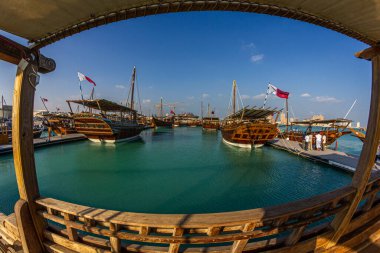 Katara plajında geleneksel ahşap kayıklar (dhows) Katar bayrağı ve gökyüzünde bulutlar olan Katar gündüz görüşü