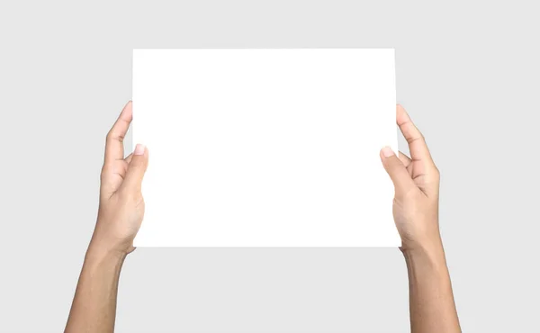 女性的手拿着纸在柔软的灰色背景上 空白白纸 裁剪路径 图库照片