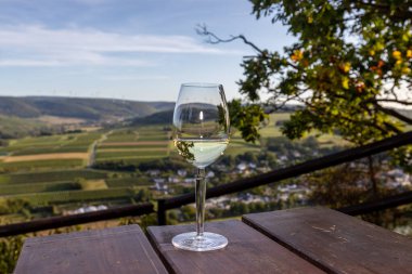 Glas of white wine at a scenic point near Brauneberg on river Moselle with view of landscape in the background clipart
