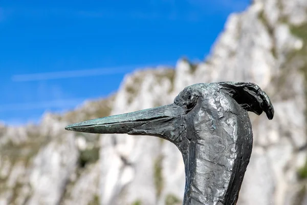 Escultura de pájaro de metal en frente y rocas altas en la parte posterior — Foto de Stock