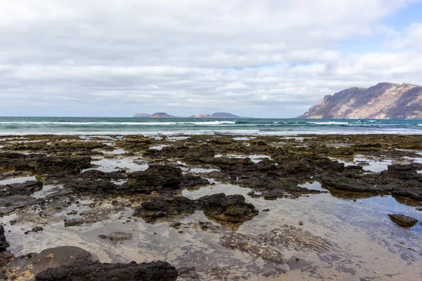 Coastline and sand beach Playa de Famara with mountain range and — Stock Photo, Image