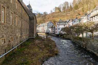 Monschau, Eifel 'de nehir kıyısında yarı keresteli evler ve kilise.