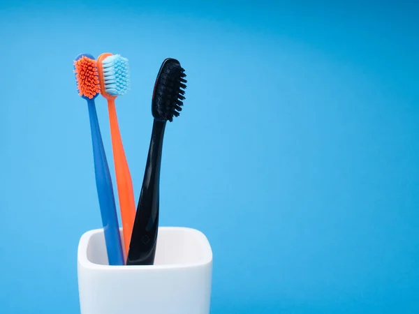 Three Toothbrushes Black Blue Orange Oral Care White Toothbrush Holder — Stock Photo, Image