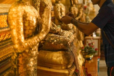 Bir adam bazı altın varak Buda resim koymak..