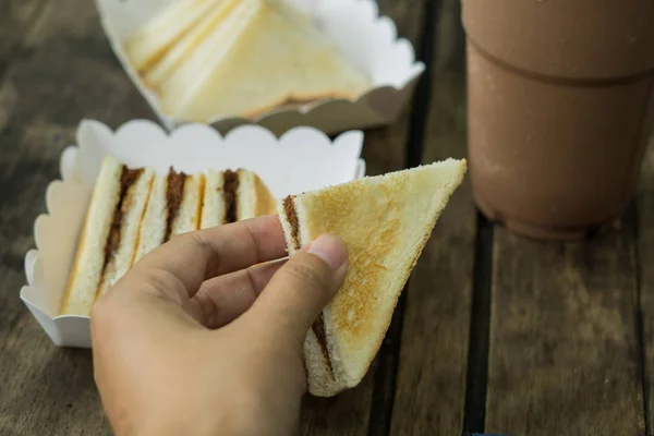手拿着新鲜的三明治在木桌上的咖啡机 — 图库照片