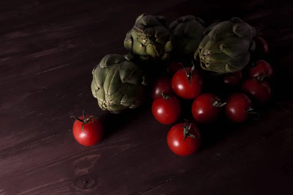 Tomates y alcachofas sobre una mesa de madera — Foto de Stock