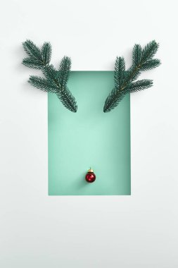 Kırmızı Xmas topundan yapılmış ren geyiği yüzü ve beyaz kenarlı yemyeşil bir dal