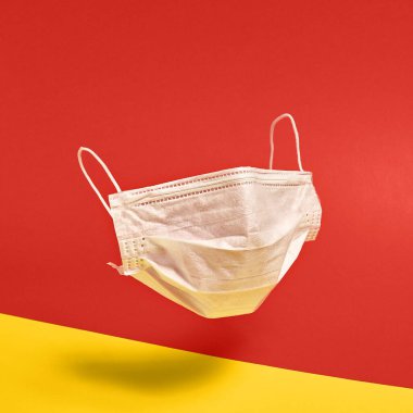 Kırmızı ve sarı arka planda cerrahi yüz maskesi. Asgari tıbbi konsept. Tıbbi ekipman