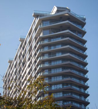 Deniz kıyısında bir park alanına inşa edilmiş ön camlı modern yüksek katlı bina.