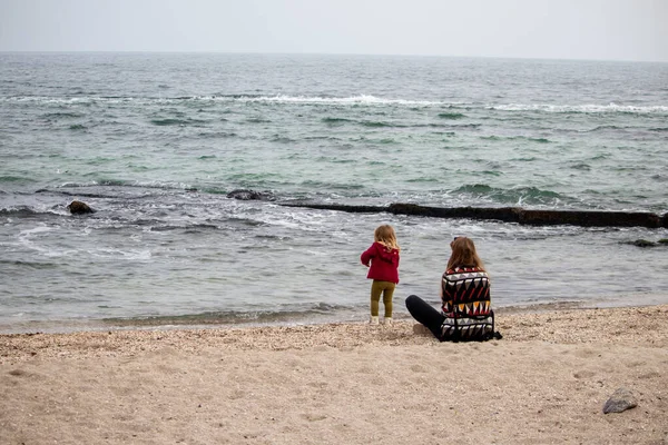 Ragazza con sua madre sulla sabbia vicino all'acqua in autunno in mare — Foto Stock