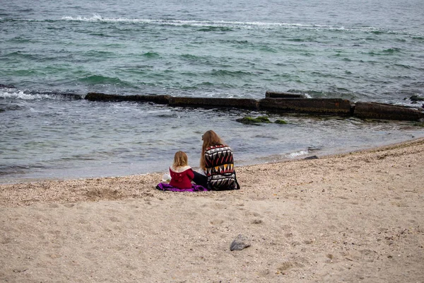 Ragazza con sua madre sulla sabbia vicino all'acqua in autunno in mare — Foto Stock