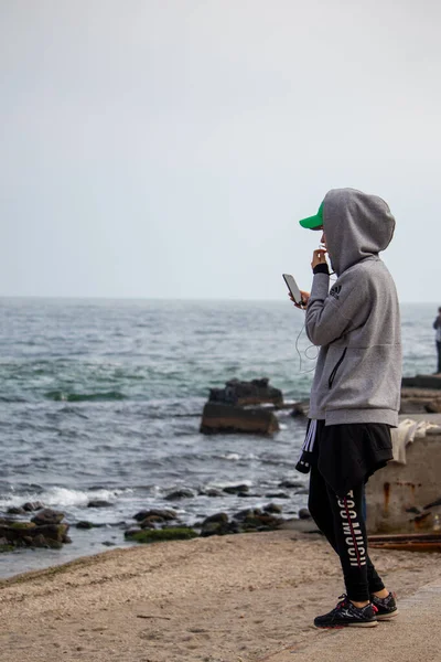 Ragazza con il telefono in mano in una corsa sulla spiaggia in autunno - Ucraina- Odessa - 10.17.2019 — Foto Stock