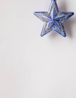 Beyaz arka planda mavi ve gümüş renkli yıldız şeklinde bir Noel oyuncağı.