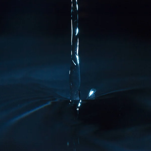 Water Spat Een Donkere Achtergrond — Stockfoto