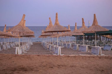Plaj şemsiyeleri ve katlanmış güneş şezlongları.