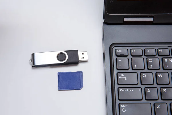 Two types of flash drives near a laptop