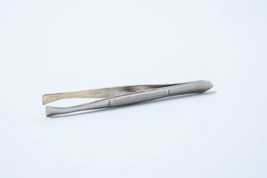 Beyaz arka planda küçük metal manikür cımbızları.