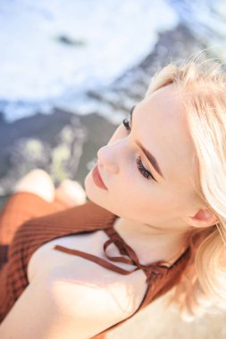 Genç sarışın kaynayan bir nehrin kıyısında elbise giymiş.