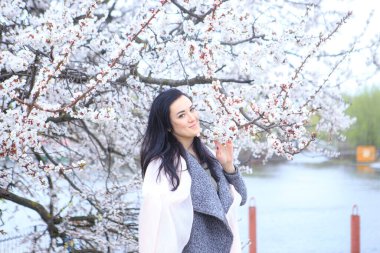 Baharda çiçek açan kiraz ağacındaki esmer kız.