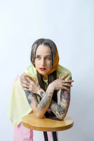Blue-eyed girl with tattoos on a white background