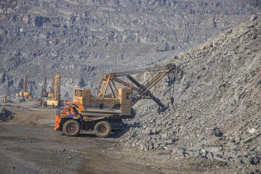 Kazıcı büyük bir çöp kamyonuna demir cevheri yüklüyor.