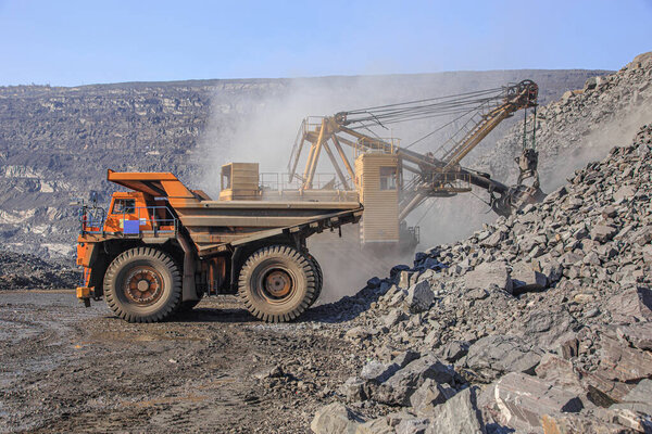 Excavator loads iron ore into a large dump truck
