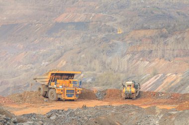 Büyük çöp kamyonu boş taşları boşaltıyor.