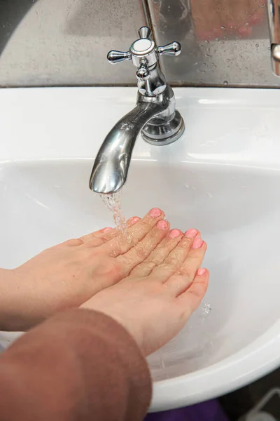 Female hands in a washstand under a stream of water