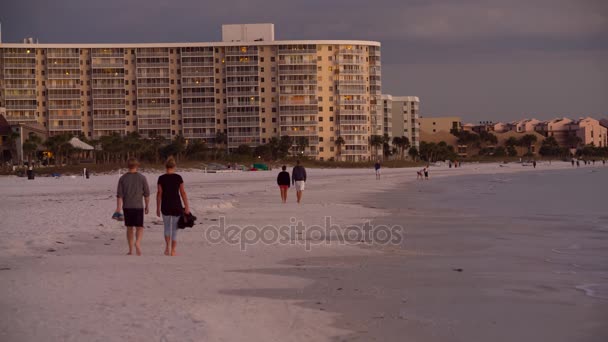 Gente caminando sobre el mar cuesta al atardecer — Vídeos de Stock