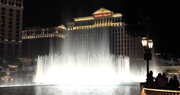 Fuente de Bellagio por la noche con una vista de fondo del hotel CaesarsPalace — Vídeos de Stock