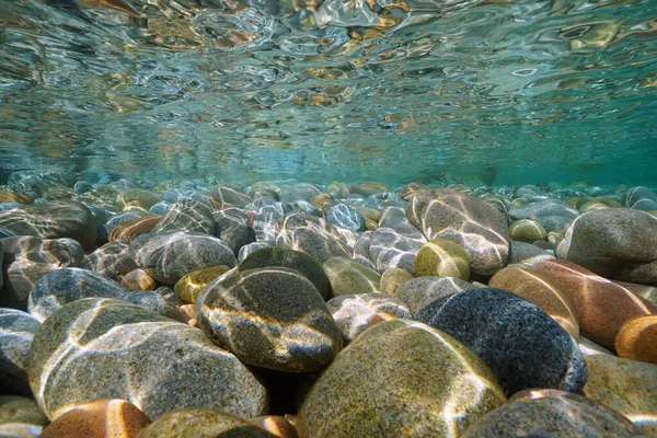 Pebbles stone underwater below water surface