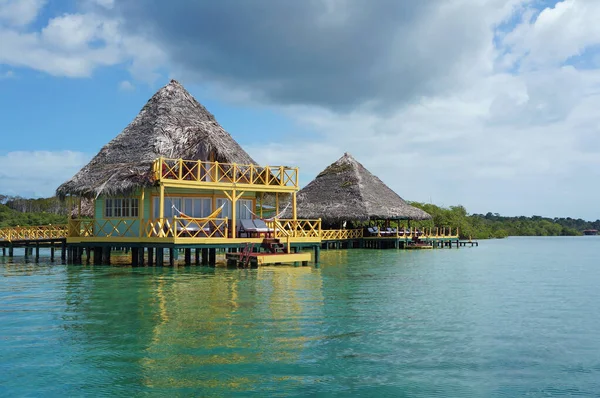 Tropical eco resort over water with thatched roof