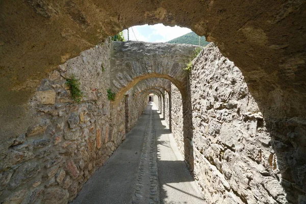 Passage under stone arches fortified village France