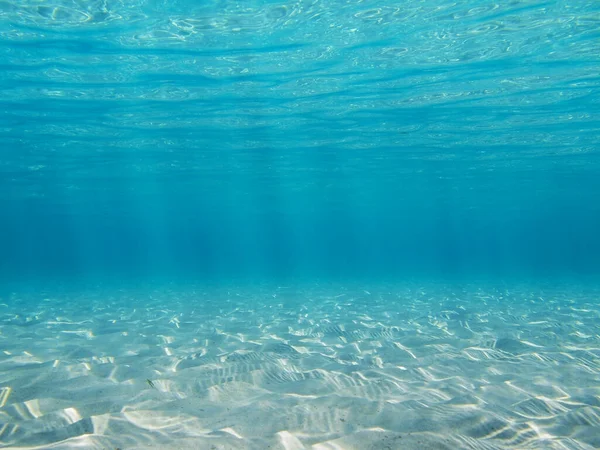 Sandy seabed with sunlight through water surface