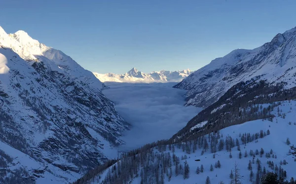 Anyagvölgy és havas hegyek naplemente kilátás téli táj Svájci Alpokban fény felhők a völgyben — Stock Fotó