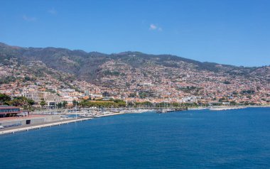 MAdeira Adası 'ndaki Funchal' da mavi gökyüzü, ülkenin başkentidir. Güzel gezinti güvertesi, küçük evler, arka planda dağlar, doğrudan denize bakan..