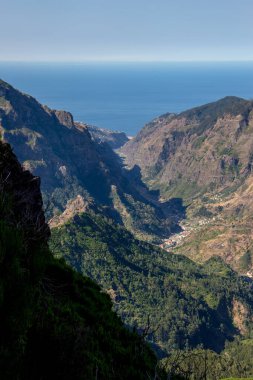 Madeira merkez dağlarında yürüyüş, güzel bir manzara, ufuk, mavi gökyüzü yolda. Muhteşem Madeira dağ manzarası, yeşil ağaçlar, küçük yapılı köyler..