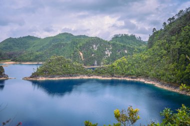 Meksika, Chiapas 'ta Lagunas de Montebello adında güzel bir göl manzarası ve arka planda ağaçlık dağlar ve bulutlu bir gökyüzü.